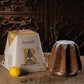 Borsari Panodoro Crema Limoncello cake packaging box shown next to a baked cake dusted with powdered sugar and a lemon on a rustic burlap surface against a dark carved wooden background.