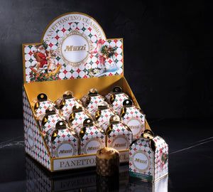 A retail display box filled with small Muzzi Panettonino Classic mini gift boxes, with one larger box standing in front on a dark reflective surface against a black background.