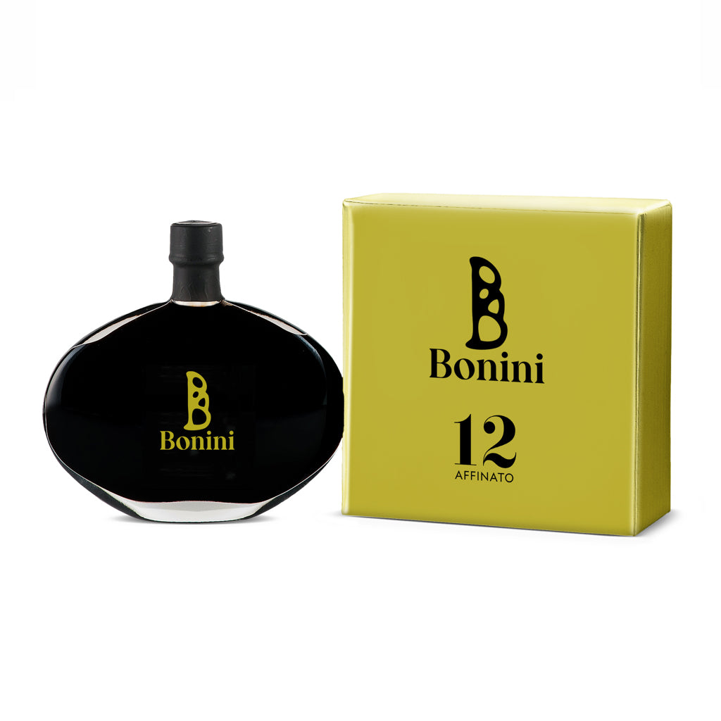 A bottle of Bonini Affinato balsamic vinegar with a black cap, placed next to its yellow packaging box with the number 12 and the Bonini logo.