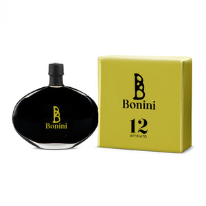 A bottle of Bonini Affinato balsamic vinegar with a black cap, placed next to its yellow packaging box with the number 12 and the Bonini logo.