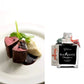 Bottle of Sua Maesta Dolce with a dish of food on a white background