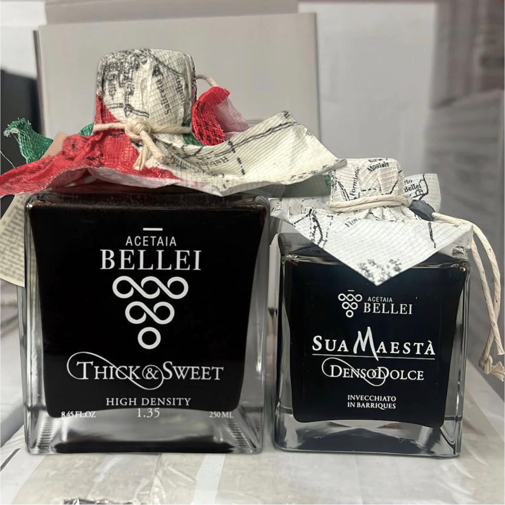 Two bottles of aceto balsamico with decorative packaging on a table.