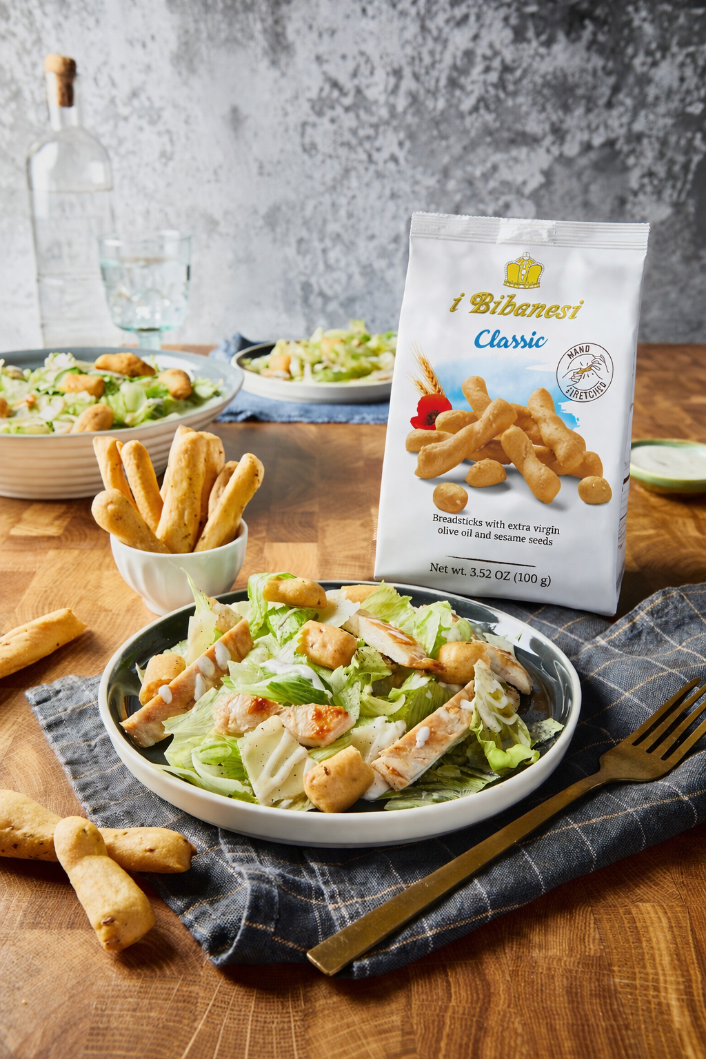 wood table with a pack of i bibanesi, some plates of cesar salads and a bowl with I Bibanesi's breadsticks 