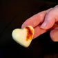 Heart-shaped cookie with a brown spot held in a hand against a dark background with aleppo chili flavor
