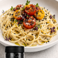 pasta plated with tomatos and black lava salt flakes