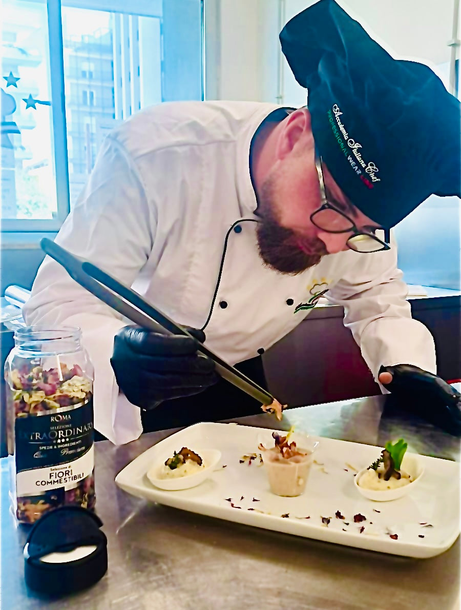 Chef preparing a dish in a kitchen with a bottle of Fracordinio on the counter with edible flowers on the top
