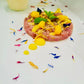 Tua tartare with yellow fruit compote and colorful edible flowers on the top and on a white surface