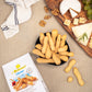 Table with a I bibanesi pack and some breadsticks in a bowl on the table, with a cutting board with some cheeses and green grapes