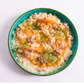 Risotto dish with sausage and herbs in a blue bowl on a white background