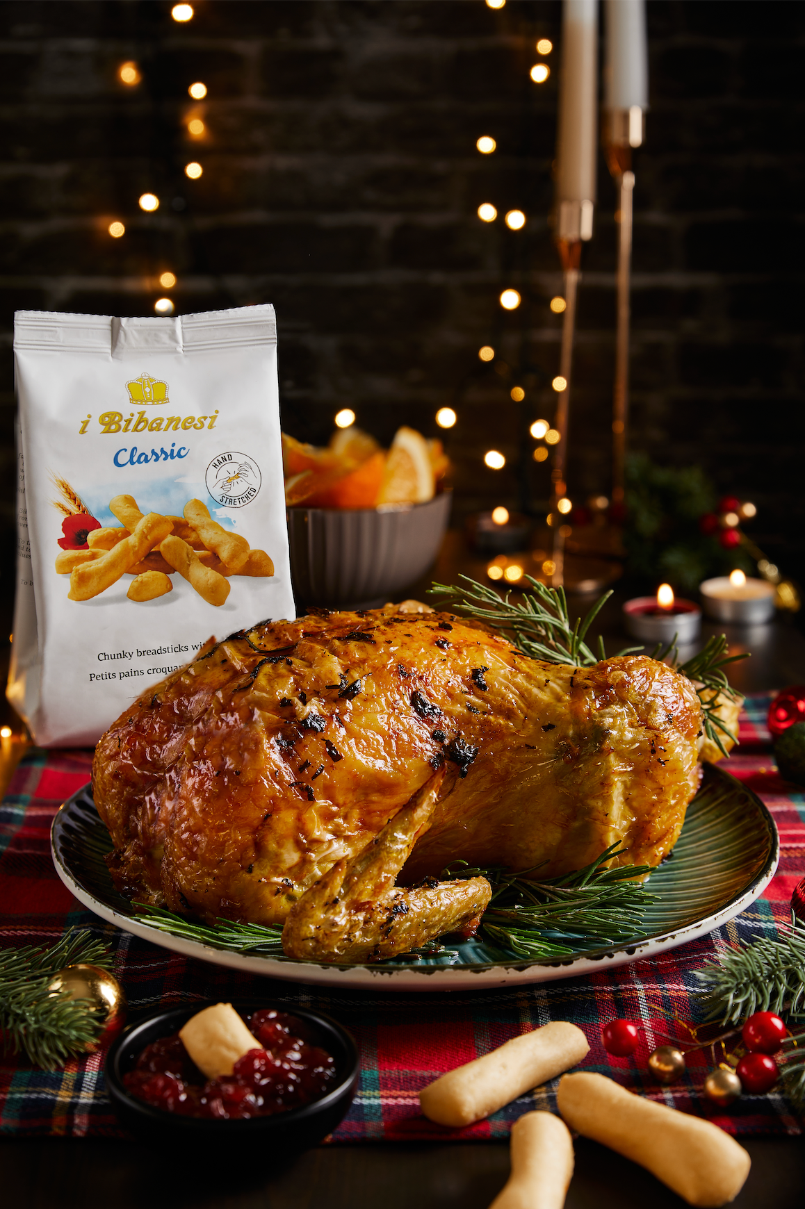christmas table with a roasted chicken on a green plate some rosemary on it and I bibanesi pack on the side abs some breadsticks on the table. Christmas background 
