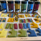 Colorful pasta shapes on a tray with paint jars in the background