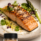 Salmon dish with smoked cyprus pyramidal salt flakes on a plate, accompanied by a jar of salt flakes. Asparaus on the side