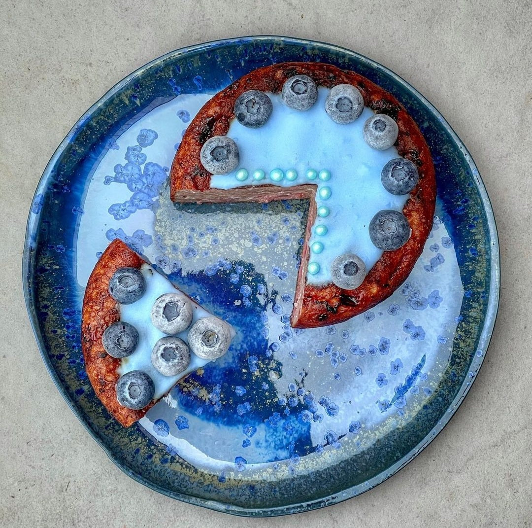 Decorative plate with a pie and blueberries on a textured surface_deep blue foodcolor