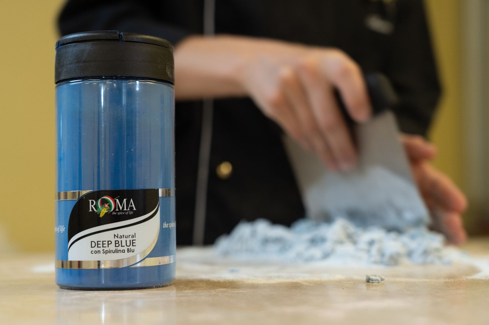 Blue container labeled 'Roma' on a table with a blurred background_ blue deep foodcolor