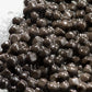 A close-up of glossy truffle pearls glistening with water, piled on a white surface.