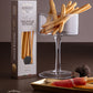 breadsticks artisanal truffle crackers shown with their branded box, served in a clear glass platter, and paired with cured ham and truffles on a gold tray against a dark brown background.