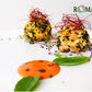 Two decorative rice balls on a white plate with 'ROMA' branding and thin chili threads on the top.