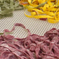 Three types of colorful pasta on a textured surface