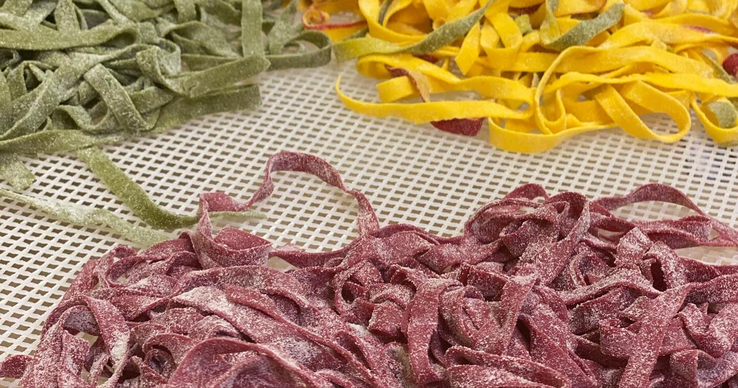 Three types of colorful pasta on a textured surface