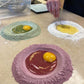 Three colored dough circles with egg yolks on a countertop.