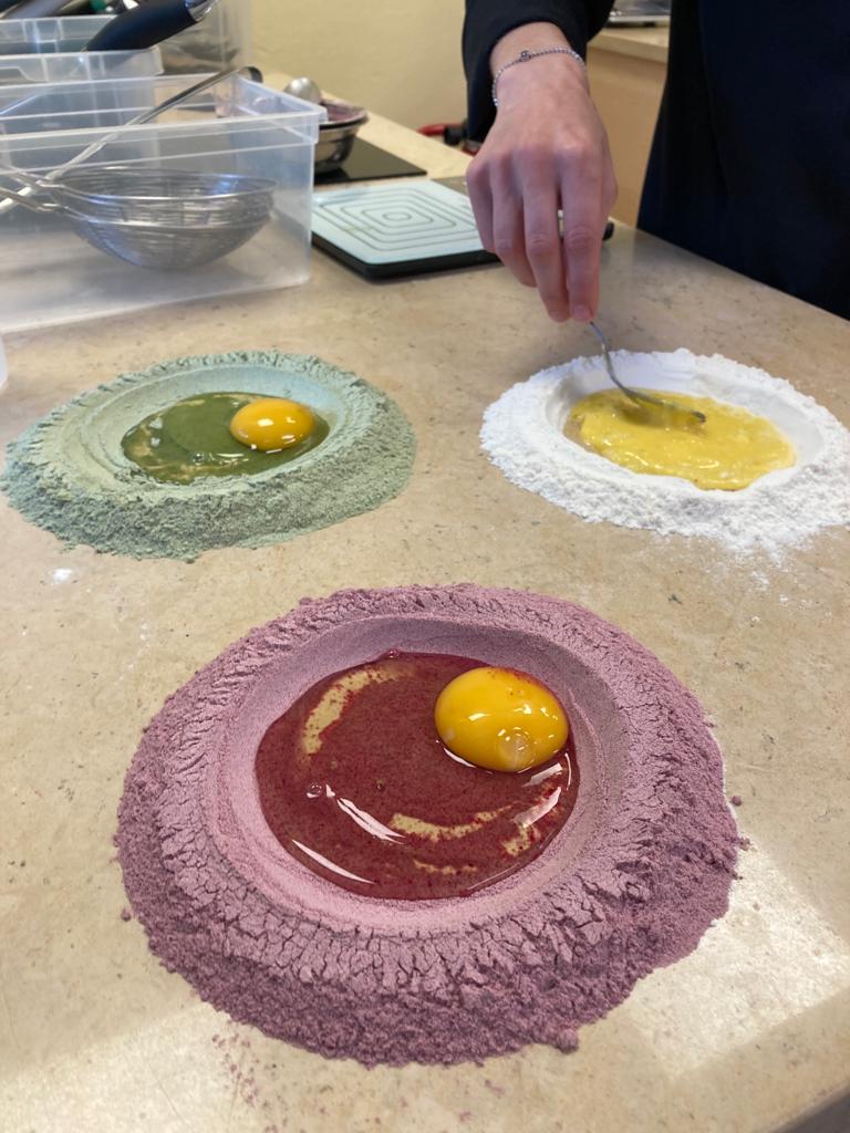 Three colored dough circles with egg yolks on a countertop.