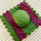 Decorative green and purple ravioli on a textured beige background