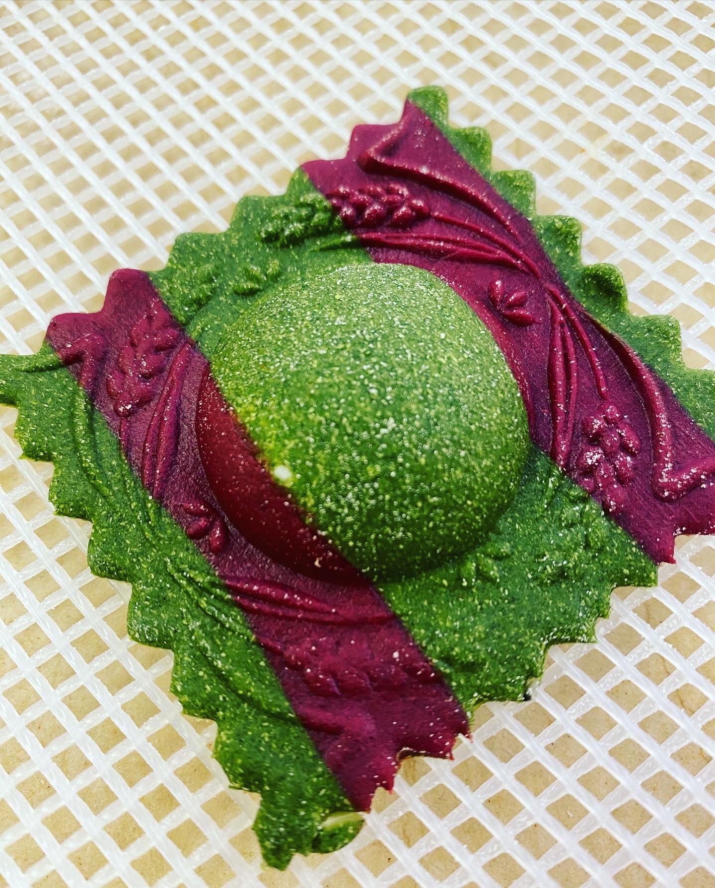 Decorative green and purple ravioli on a textured beige background