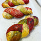 Colorful braided bread rolls on a white surface with red color food