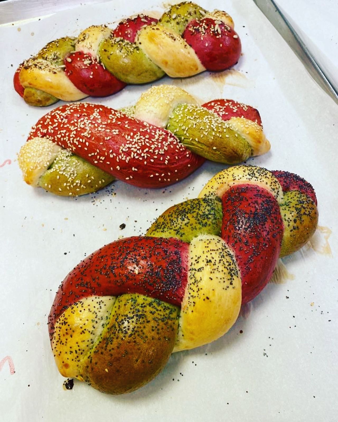 Colorful braided bread rolls on a white surface with red color food