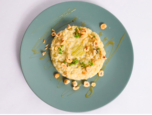 Risotto dish on a green plate with a risotto with hazelnuts, herbs and sage and lemon sauce 