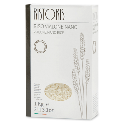A 1 kg box of Ristoris Vialone Nano Rice, featuring a white packaging design with a dark gray spine, minimalist wheat illustrations, and a circular window showing the rice grains inside.
